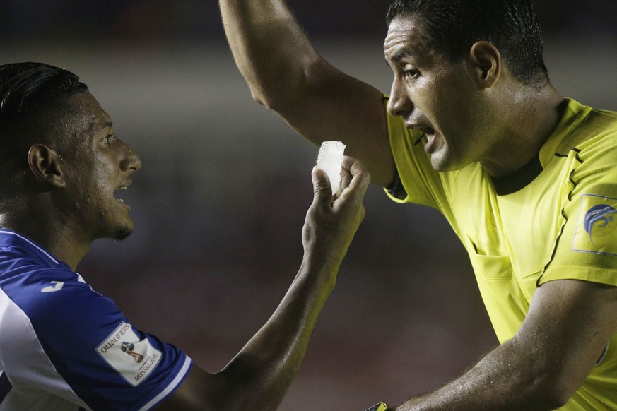 Honduras&#039; Bryan Acosta, left, shows an ice cube, thrown by fans, to referee Roberto Garcia, from Mexico, during a 2018 Russia World Cup qualifying soccer match against Panama at Rommel Fernandez  ...