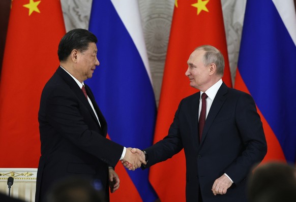 epa10535406 Chinese President Xi Jinping (L) and Russian President Vladimir Putin (R) shake hands during the signing ceremony of documents concerning the further development and cooperation between Ru ...