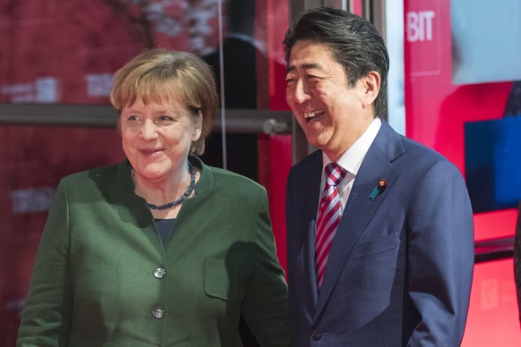 epa05858664 Japanese Prime Minister Shinzo Abe (R) and German Chancellor Angela Merkel (L) share a light moment bas they arrive for the &#039;Welcome Night&#039; opening event at the CeBIT computing t ...