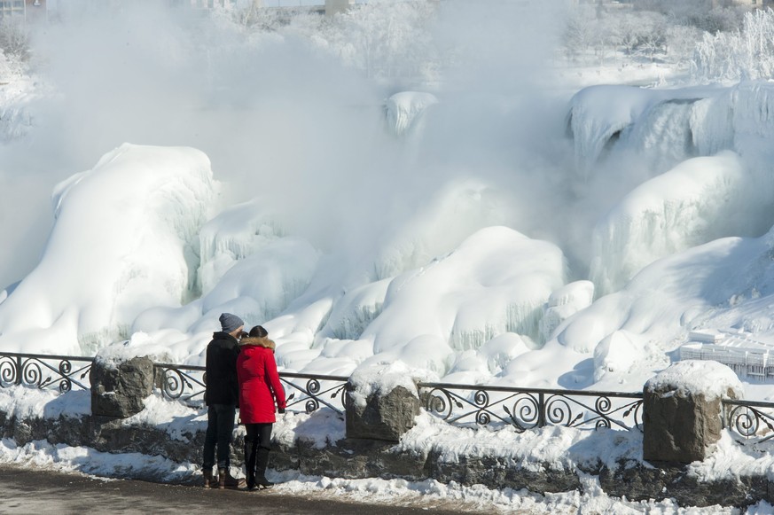 epa04629563 People view The American Falls (rear) from Niagara Falls, Canada, 20 February 2015. Recent weeks of below average temperatures has caused a build up of ice at the base of all the waterfall ...