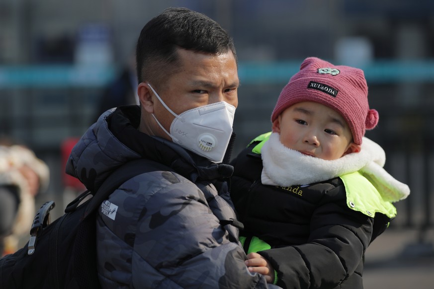 epa08161948 A Chinese man wears a mask while holding a child at Beijing Railway Station in Beijing, China, 25 January 2020. On 25 January, the National Health Commission of China confirmed the death t ...