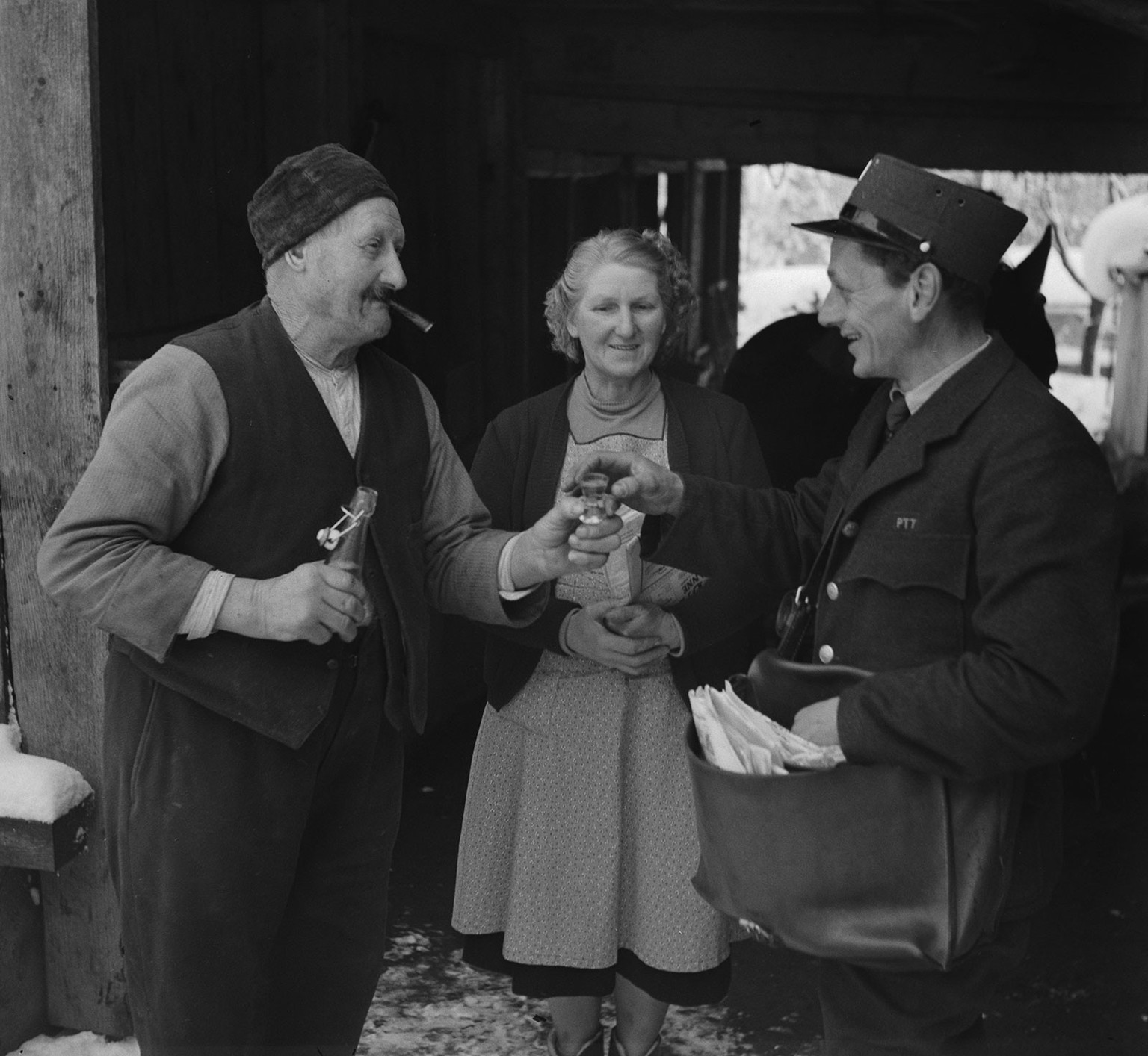 Ein Bauer offeriert dem Pöstler einen Schnaps bei der Postübergabe, 1952.
https://permalink.nationalmuseum.ch/100639213