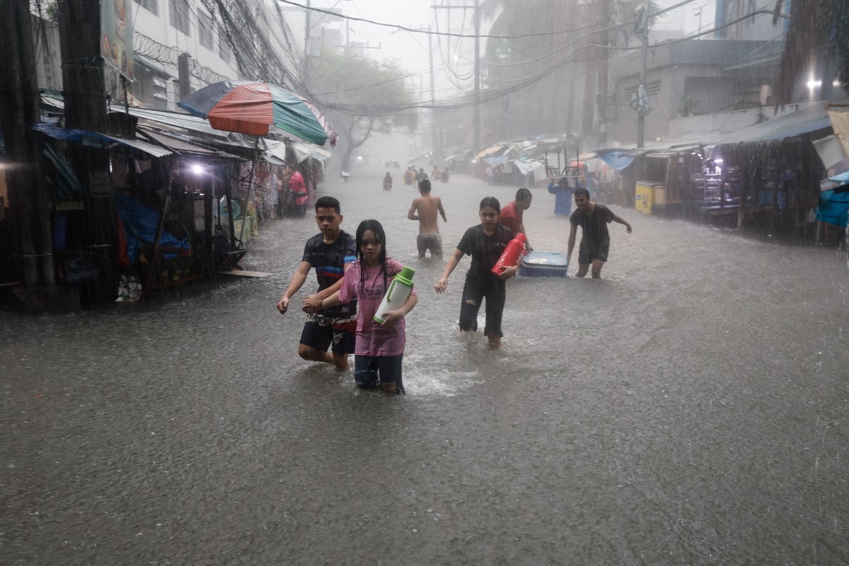 epa11493393 Residents walk in a flooded area following monsoon rainfall in Quezon City, Metro Manila, Philippines, 24 July 2024. Monsoon rains caused by typhoon Gaemi resulted in flooding in Metro Man ...