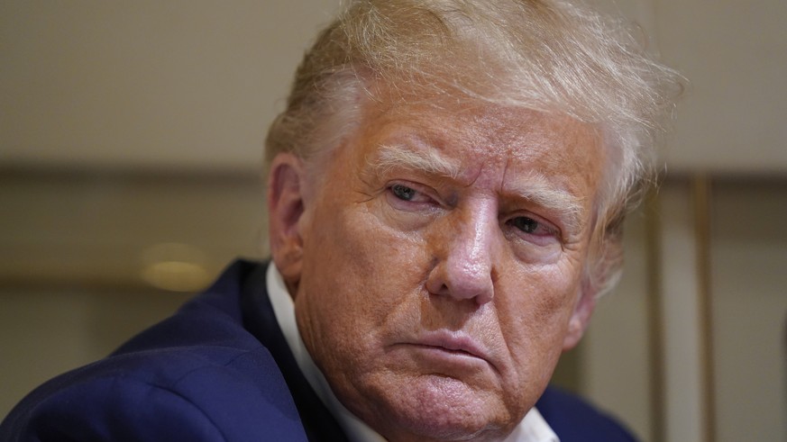 FILE - Former President Donald Trump listens as he speaks with reporters while in flight on his plane after a campaign rally at Waco Regional Airport, in Waco, Texas, March 25, 2023, while en route to ...