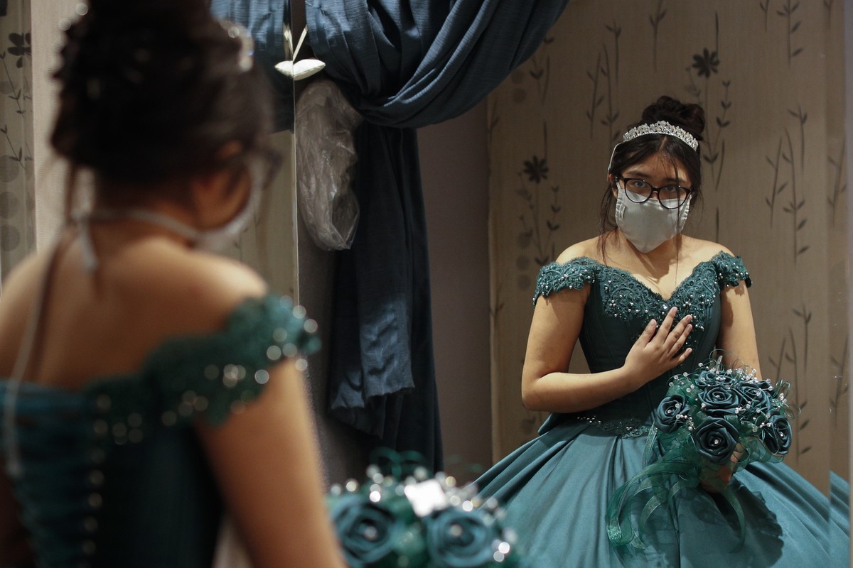 Ximena Canejo Hernandez checks her reflection in a mirror as she tries on her chosen Quinceanera dress, in central Mexico City, Friday, July 10, 2020. Ximena's family, wanting to give her a tradi ...