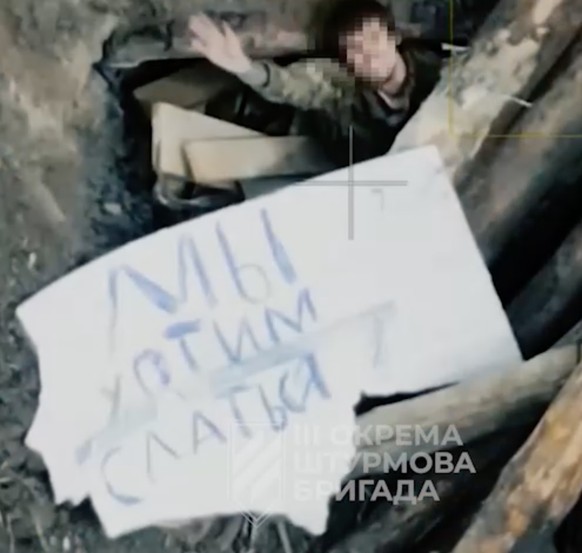 Karton mit Schriftzug «Wir wollen uns ergeben». Russische Soldaten ergeben sich im Juni 2025 einer ukrainischen Drohne. Region Charkiw.