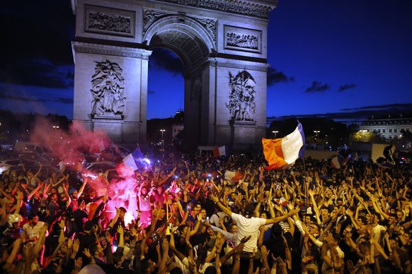 People celebrate on the Champs Elysees avenue, with the Arc de Triomphe in background, after the semifinal match between France and Belgium at the 2018 soccer World Cup, Tuesday, July 10, 2018 in Pari ...