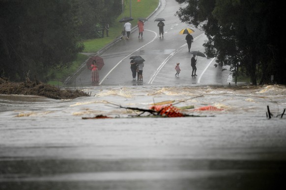epa09877382 People watch on from the north side as the North Richmond bridge is seen completely submerged by floodwater from the swollen Hawkesbury river, at Richmond, New South Wales, Australia, 08 A ...