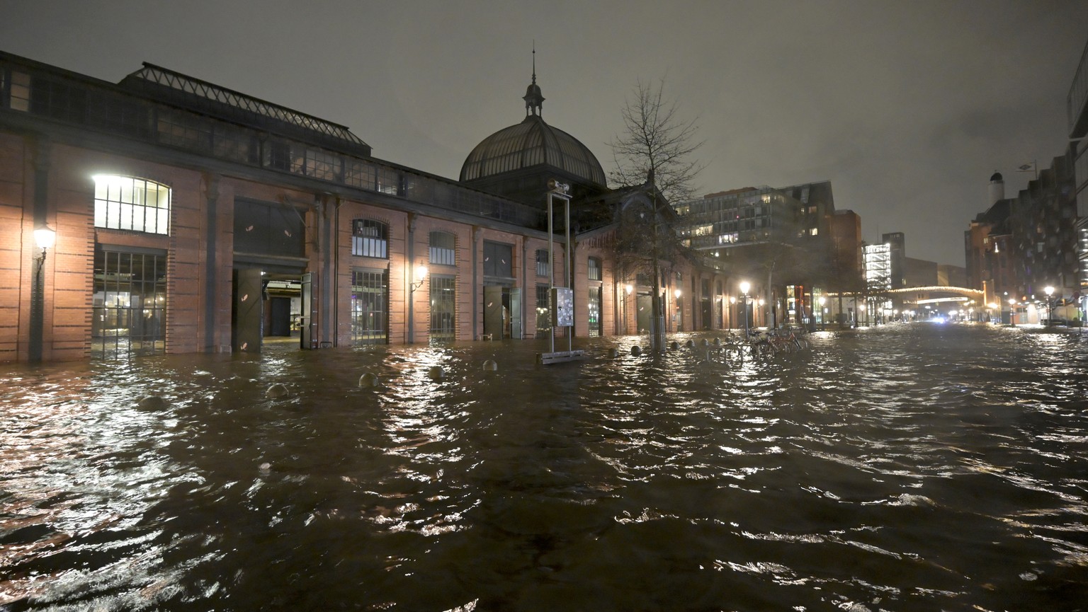 epa11040415 Water from the Elbe is pushed onto the Hamburg fish market during a storm flood in Hamburg, Germany, 21 December 2023. Germany has raised yellow weather alerts for 21-22 December as Storm  ...