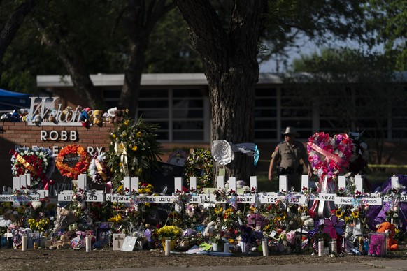 FILE - Flowers and candles are placed around crosses on May 28, 2022 at a memorial outside Robb Elementary School in Uvalde, Texas, honoring those killed in the school shooting a few days before…