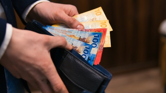 formell gekleideter Mann zählt Schweizer Franken-Banknoten. Konzept für Wirtschaft, Investitionen und Finanzen in der Schweiz