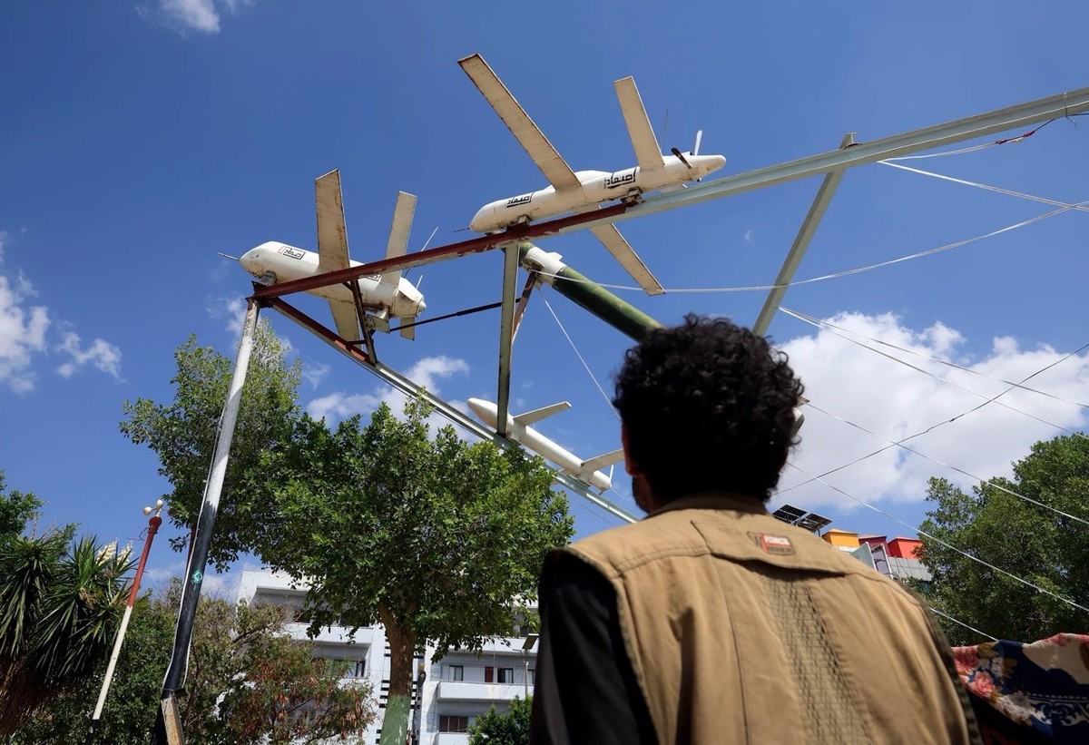 A Sanaa, un passant observe des drones de fabrication houthie exposés en plein air.