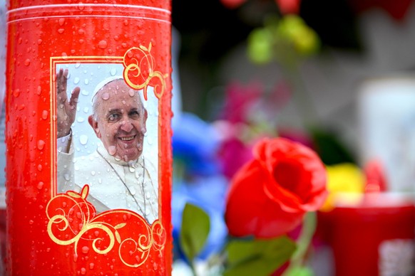 epa11921920 Candles, flowers and portraits are placed around the statue of late Pope John Paul II outside the Agostino Gemelli Hospital where Pope Francis is hospitalized in Rome, Italy, 24 February 2 ...
