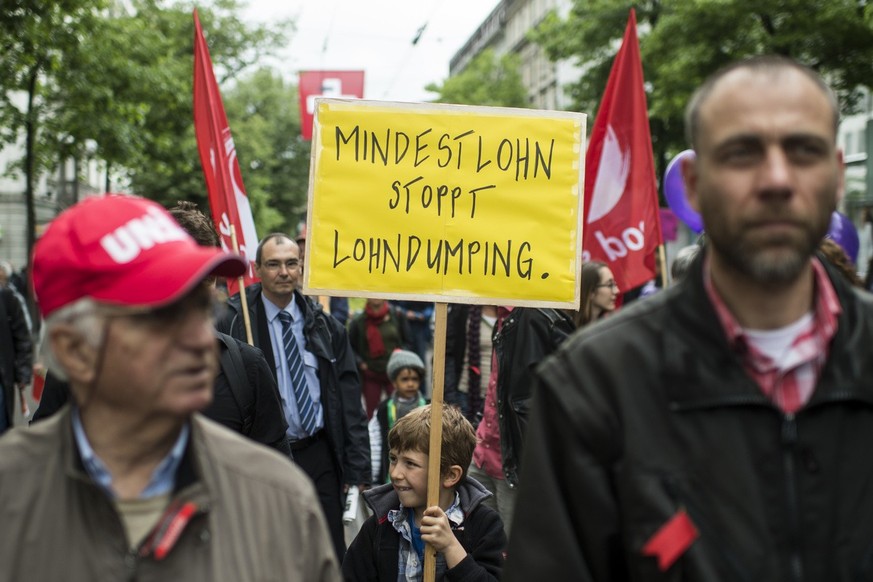 Ein junger Demonstrant traegt ein Transparent zur Mindestlohninitiative, am traditionellen 1. Mai-Umzug am Donnerstag, 1. Mai 2014, dem Tag der Arbeit, in Zuerich. (KEYSTONE/Ennio Leanza)