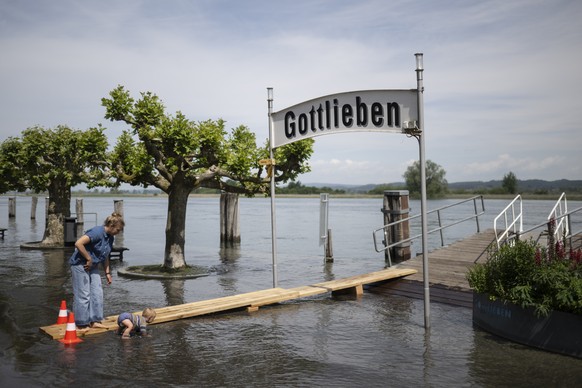 Menschen vergnuegen sich am Seerhein, der bei Hochwasser ueber die Ufer getreten ist, am Donnerstag, 6. Juni 2024, in Gottlieben. Der Seerhein fliesst zwischen Ober- und Untersee des Bodensees. Fuer d ...