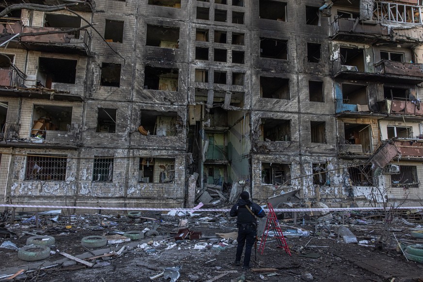 epa09824623 A Ukrainian police officer stands guard next to the residential building which was hit by the Russian artillery shelling, in Kyiv (Kiev), Ukraine, 14 March 2022. At least two people have b ...