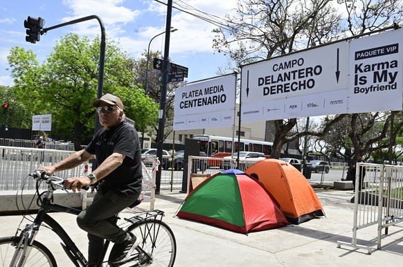 epa10964755 A man ride a bicycle past tents set up by fans of US singer Taylor Swift at the Mas Monumental stadium before the concerts she will give in Buenos Aires, Argentina, 08 November 2023. With  ...