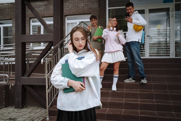 Teenage friends bullying student with books at schoolyard model released, Symbolfoto property released, MDOF02127