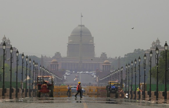 A construction worker walks across a mirage created on a road due to very hot weather in New Delhi, India, Monday, May 2, 2022. An unusually early and brutal heat wave is scorching parts of India, whe ...