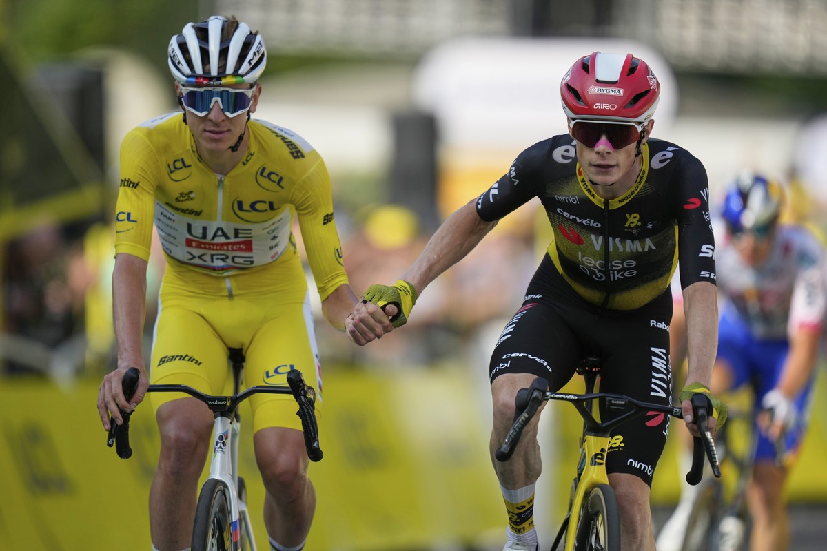 Slovenia's Tadej Pogacar, wearing the overall leader's yellow jersey, and Denmark's Jonas Vingegaard, cross the finish line hand-in-hand of the the tenth stage of the Tour de France cyc ...