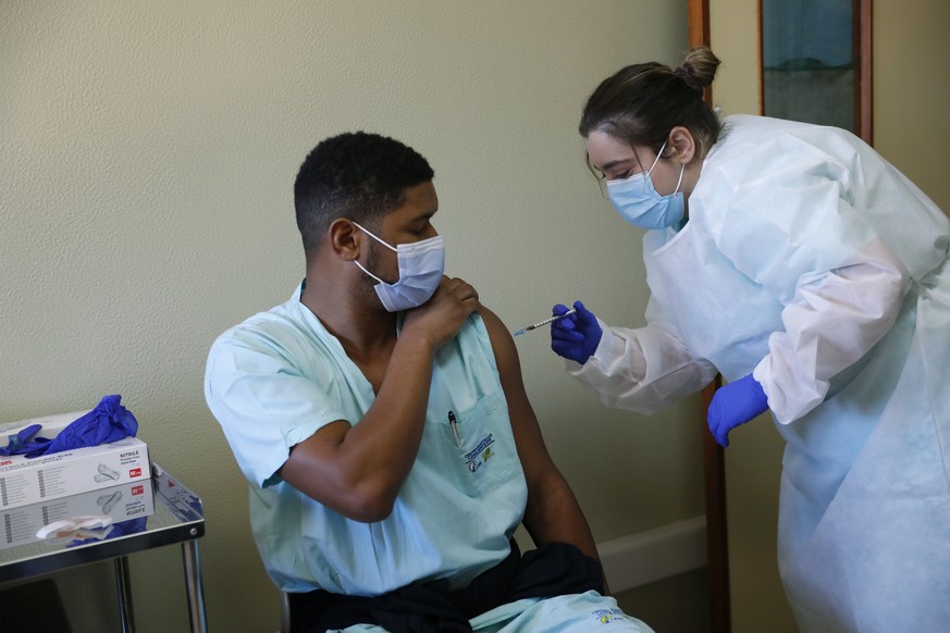 A health care worker receives a dose of the Pfizer-BioNTech COVID-19 vaccine at the Santa Maria hospital in Lisbon, Sunday, Dec. 27, 2020. Portugal started its vaccination program on Sunday with medic ...