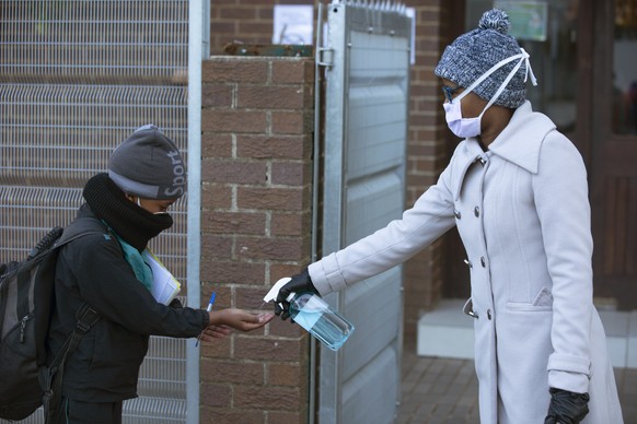 A pupil's hands are sanitised on returning to school in Johannesburg, Monday July 6, 2020, as more learners were permitted to return to class. Schools were shut down in March prior to a total country  ...