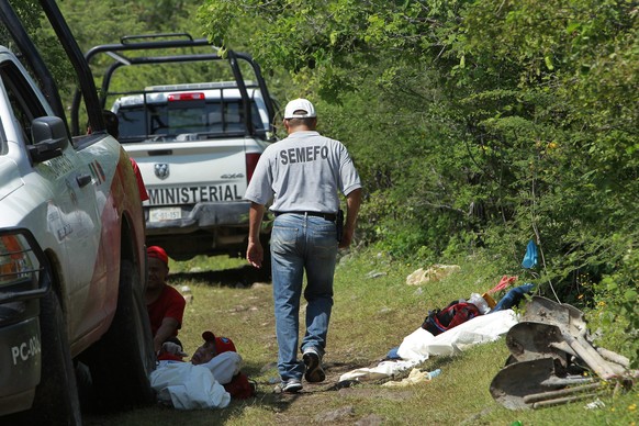 Forensiker untersuchen das Gelände, wo das Massengrab entdeckt worden ist.