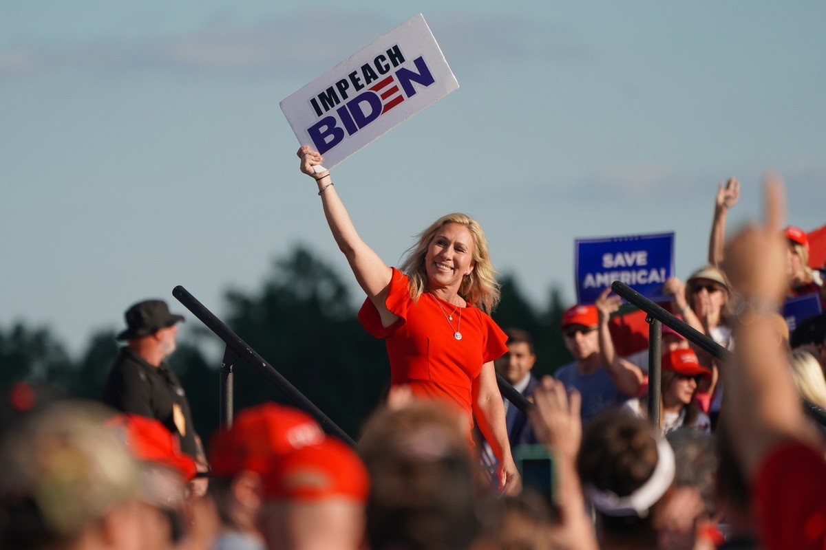 epa09488848 Republican congresswoman Marjorie Taylor Greene waves an 'Impeach Biden' placard at a rally sponsored by 'Save America' at the Georgia National Fairgrounds in Perry, Ge ...