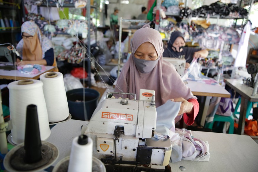 epa09050502 Workers sew clothes at a home-based apparel production operation in Bogor, Indonesia, 04 March 2021. Before the coronavirus pandemic hit, the garment industry in Indonesia produced various ...