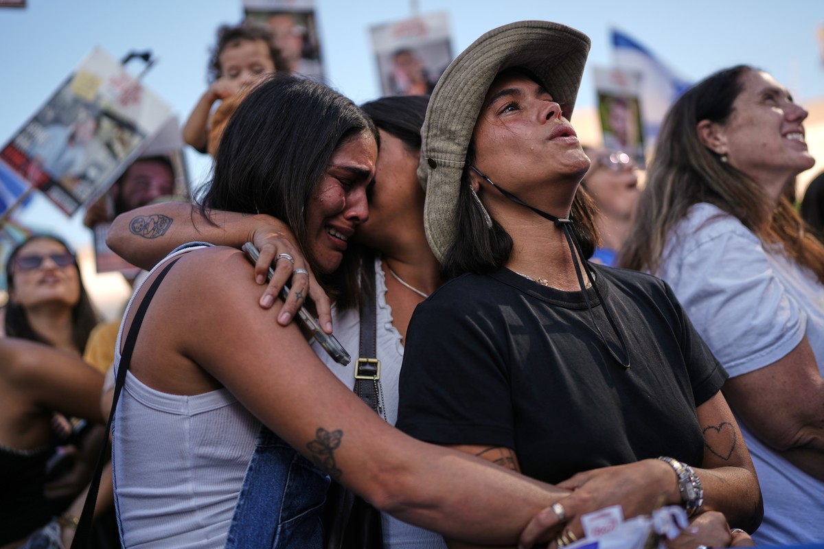 People react as they gather to watch a live broadcast of Israeli hostages released from Gaza at a plaza known as hostages square in Tel Aviv, Israel, Monday, Oct. 13, 2025. The release took place as p ...
