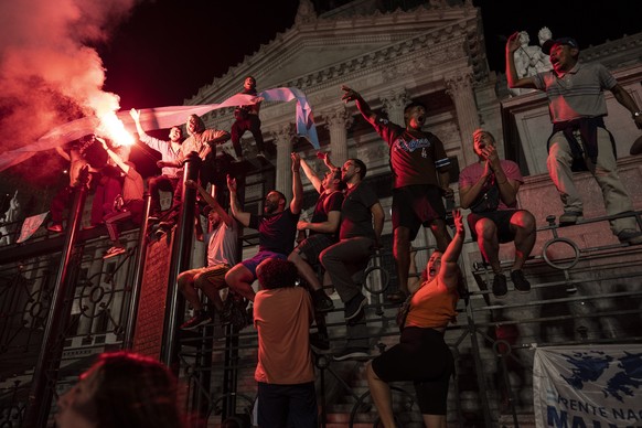 FILE - Protesters chant anti-government slogans standing on the bars that protect the National Congress during a protest against government economic measures in Buenos Aires, Argentina, Dec. 21, 2023. ...