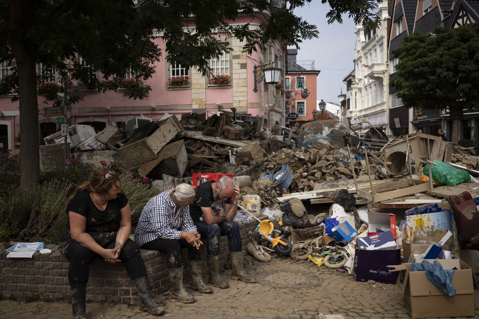 People rest from cleaning up the debris of the flood disaster in Bad Neuenahr-Ahrweiler, Germany, Monday July 19, 2021. More than 180 people died when heavy rainfall turned tiny streams into raging to ...