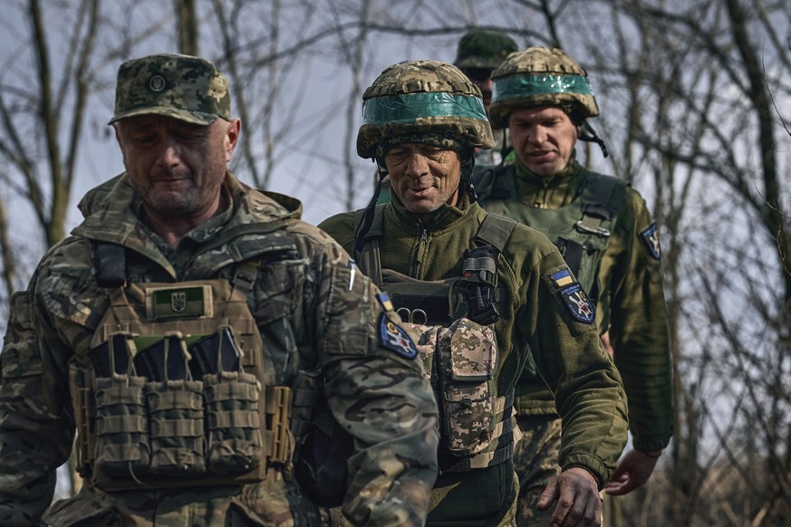 Ukrainian soldiers of the 28th brigade walk together at their position on the frontline near Bakhmut, Donetsk region, Ukraine, Monday, March 27, 2023. (AP Photo/Libkos)