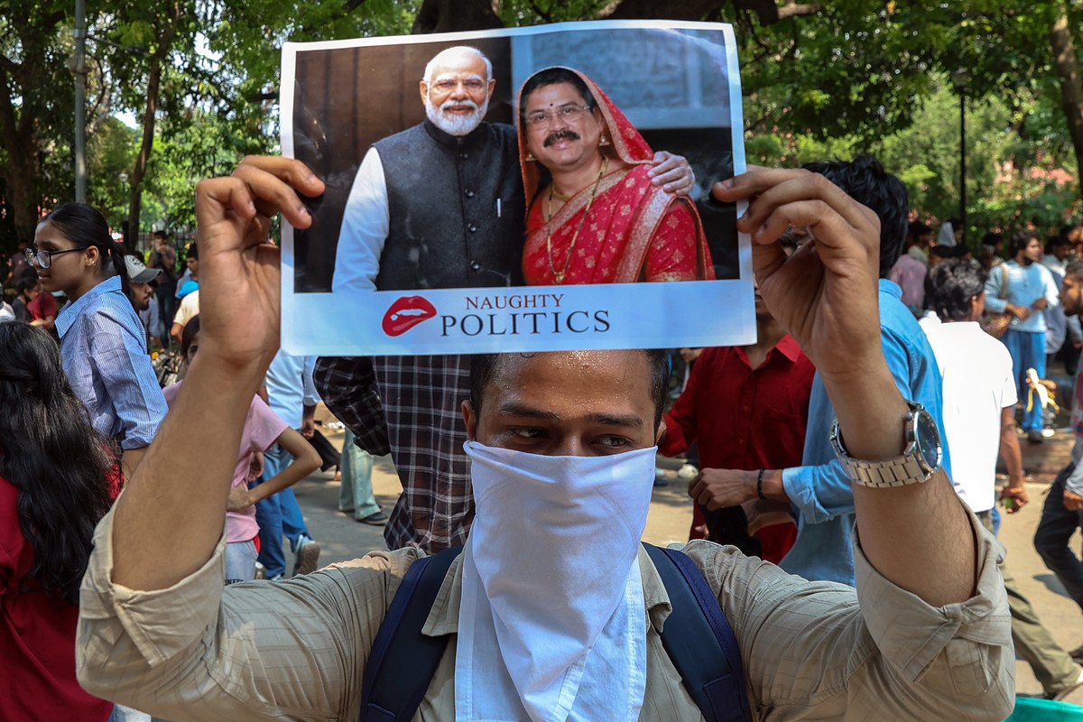 epa13127624 A supporter of India's Cockroach Janta Party (CJP) holds a placard depicting Indian Prime Minister Narendra Modi (L) and Union Minister of Education Dharmendra Pradhan as their demons ...