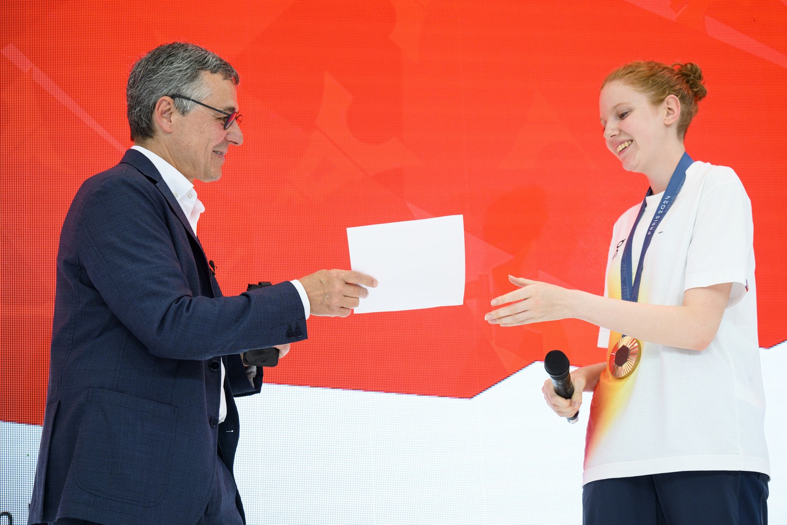 Swiss Federal Councillor Ignazio Cassis, left, speaks with Audrey Gogniat of Switzerland bronze medal winner in the women&#039;s 10m air rifle competition, at the reception in the maison suisse at the ...