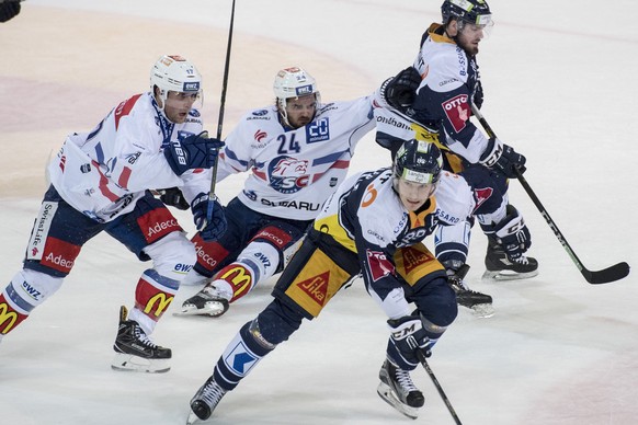 Phil Baltisberger, mitte, vom ZSC im Spiel gegen Nolan Diem, rechts hinten, und Sven Senteler, vorne, von Zug im ersten Eishockey Playoff-Viertelfinalspiel der National League zwischen dem EV Zug und  ...