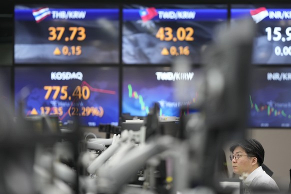 A currency trader watches computer monitors near the screens showing the foreign exchange rates at a foreign exchange dealing room in Seoul, South Korea, Wednesday, March 15, 2023. Asian stock markets ...