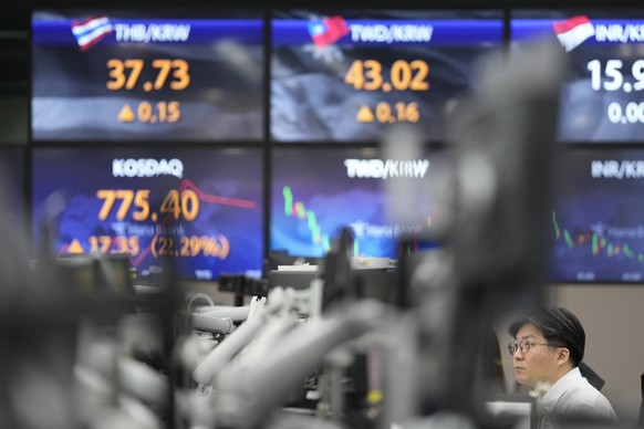 A currency trader looks at computer screens near the screens showing exchange rates at a currency exchange office in Seoul, South Korea, Wednesday, March 15, 2023. Asian stock markets…