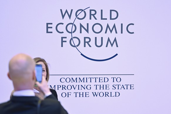 epa10417581 A man takes a picture of a woman in front of the WEF logo on the closing day of the 53rd annual meeting of the World Economic Forum, WEF, in Davos, Switzerland, 20 January 2023. The meetin ...