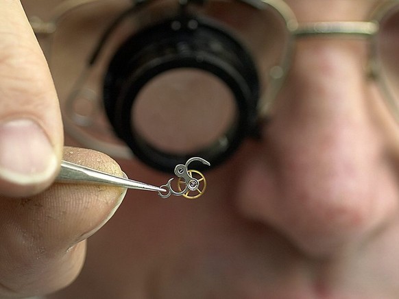 Un horloger de la firme Patek Philippe travaille sur un tourbillon de montre, lors du reportage a la manufacture horlogere Patek Philippe de Plan-les-Ouates Geneve, ce 11 novembre 2005. (KEYSTONE/Sand ...