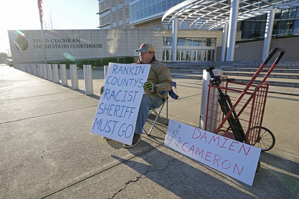 John Osborne, 62, of Jackson, sits outside the Thad Cochran United States Courthouse in Jackson, Miss., Tuesday, March 19, 2024, with signs of support for the two men abused by then six Mississippi Ra...