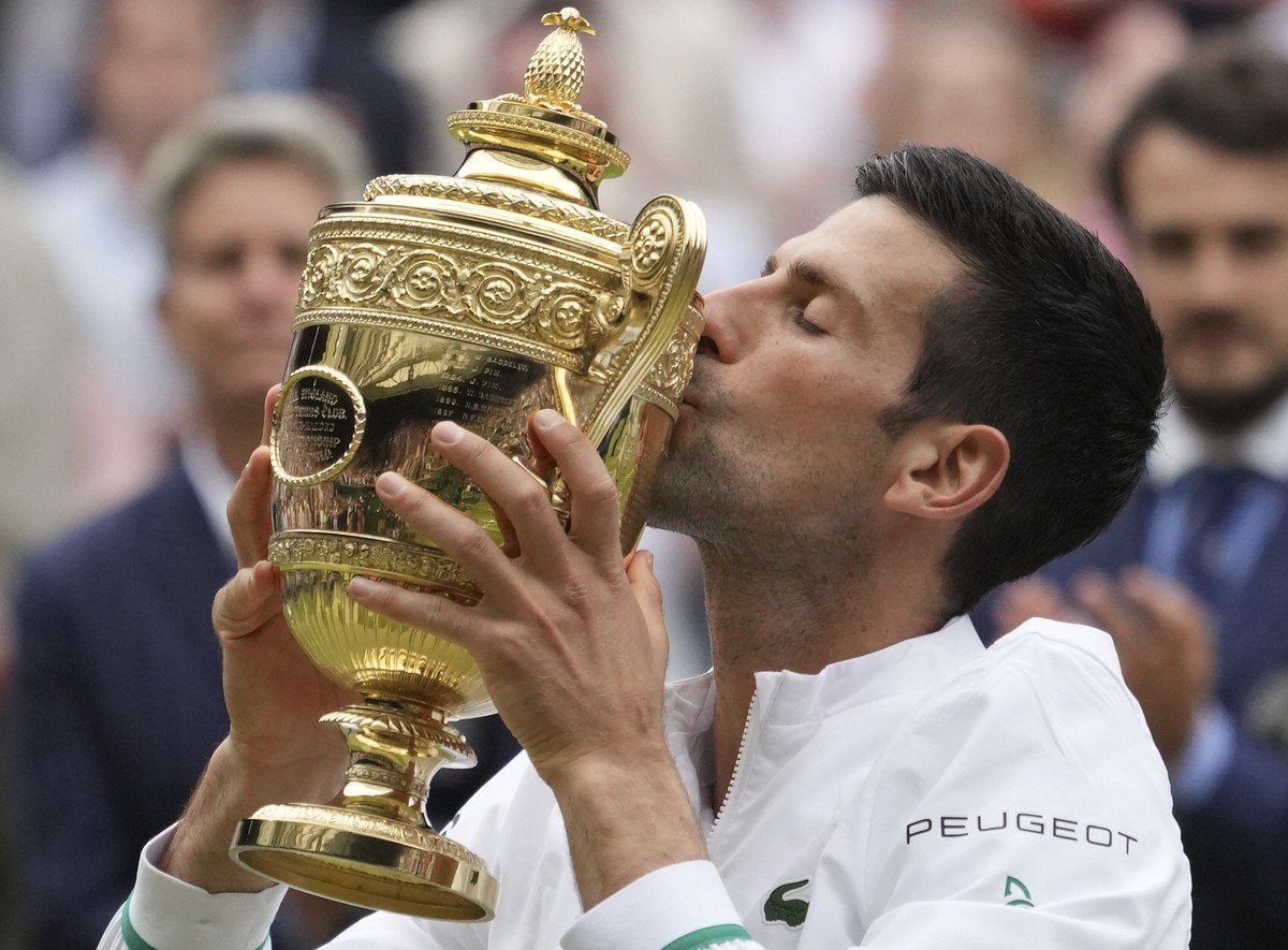 Serbia's Novak Djokovic kisses his winner's trophy and celebrates his victory over Italy's Matteo Berrettini during the men's singles final match on day thirteen of the Wimbledon T ...