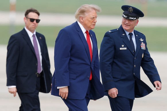 President Donald Trump, center, is escorted by Air Force Col. Christopher M. Robinson, commander of the 89th Airlift Wing, right, as he walks from Marine One to Air Force One, at Joint Base Andrews, M ...