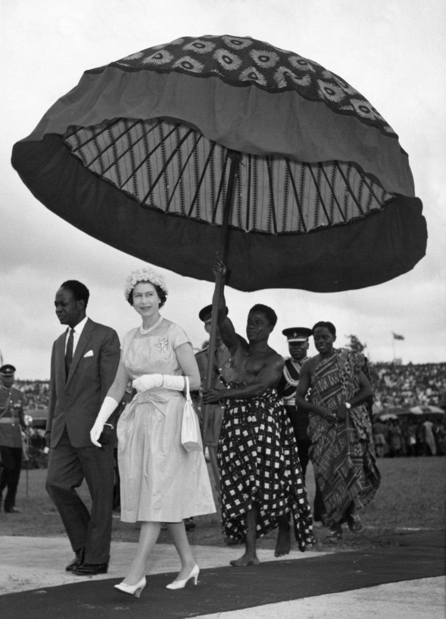 Britain&#039;s Queen Elizabeth II and Ghana&#039;s President Kwame Nkrumah walk under the shade of a huge umbrella at Kumasi Sports Stadium on Nov. 14, 1961. The Queen and Duke of Edinburgh (unseen) w ...