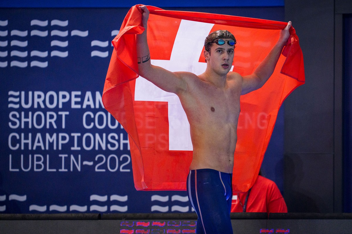 Swiss Swimmer Noe Ponti celebrates with a Swiss flag on his way out after winning in the Men's 200m Butterfly Final during the European Aquatics Short Course Swimming Championships in Lublin, Pol ...