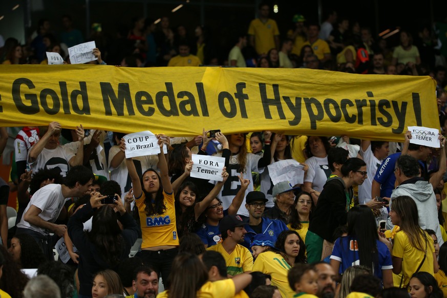 FILE - In this Aug. 12, 2016 file photo, fans hold signs against interim Brazilian President Michel Temer during a quarter-final match at the women&#039;s Olympic football tournament between Brazil an ...