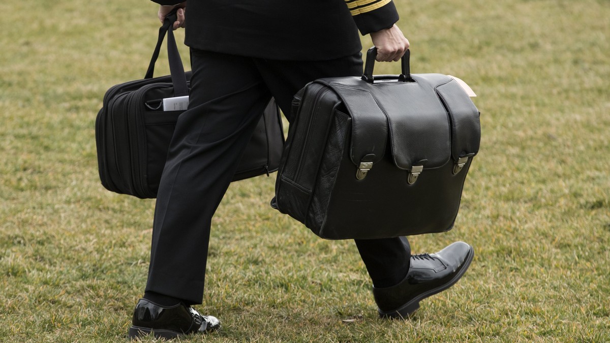 epa05769612 A military aid carries the so-called 'Nuclear Football' aboard the 'Marine One' helicopter in which US President Donald J. Trump was waiting to depart the South Lawn of ...