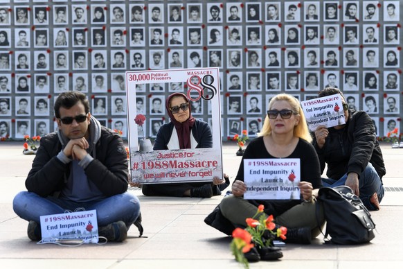 epa06207072 People protest in front of a wall of photos of victims of the 1988 Massacre of political prisoners in Iran during an exhibition at the Palais des Nations in front of the United Nations (UN ...