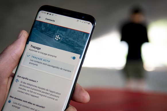A man looking at a smartphone with the tracing app SwissCovid, using Decentralized Privacy-Preserving Proximity Tracing (DP-3T), during the state of emergency of the coronavirus disease (COVID-19) out ...