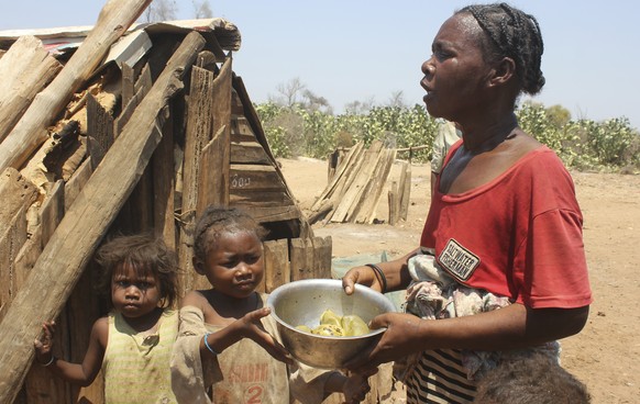 Toharano, mother of 18 children, with two of her children, holds a bowl in the village of Ankilimarovahatsy, Madagascar, Monday, Nov. 9, 2020. As a consequence of three straight years of drought, alon ...